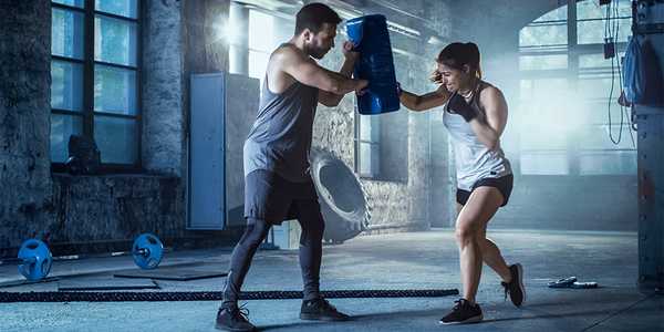 A trainer helping a woman to learn boxing.